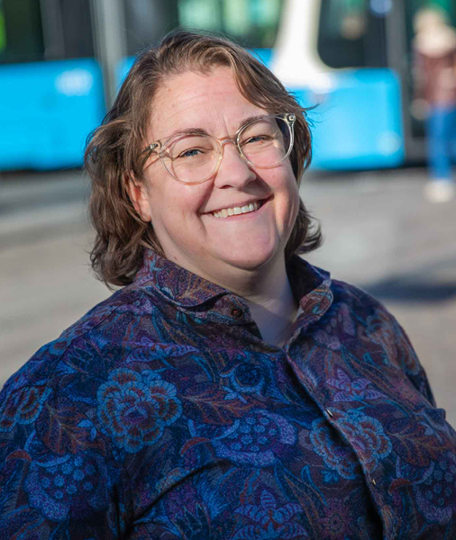 Ett portr tt av en person som tittar in i kameran och en sp rvagn i bakgrunden.